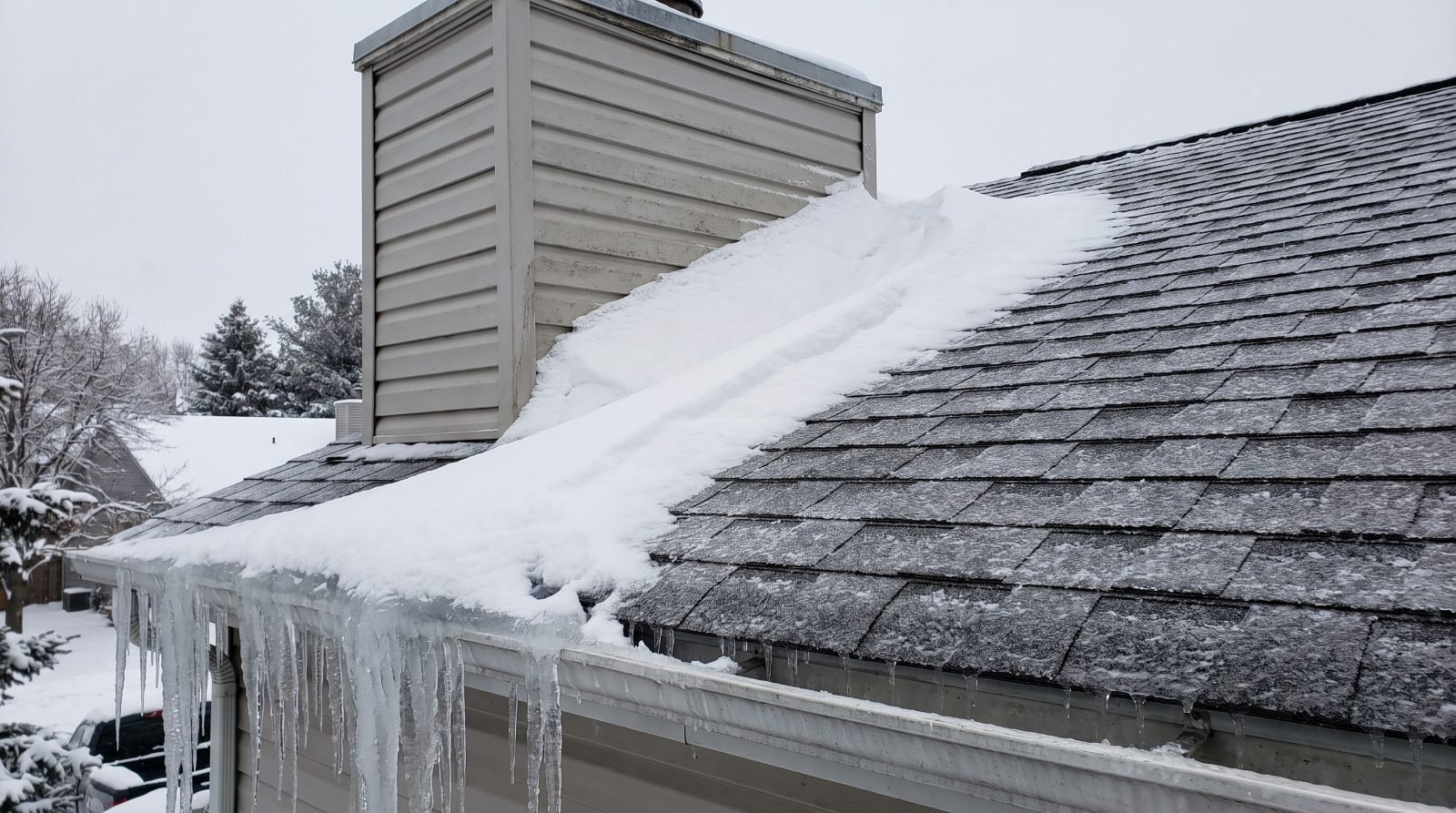 Snow on a suburban roof with drifting packed against the up-slope side of a chimney chase